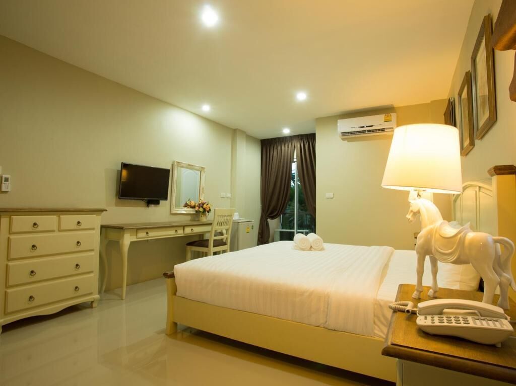 Une chambre d’hôtel équipée d’un lit, d’un bureau, d’une chaise, d’une télévision, d’une lampe et d’un téléphone.