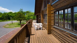 Une terrasse en bois avec des sièges pour l’extérieur et une vue sur la verdure environnante.