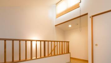 A room with tatami flooring, a wooden bench, a low wooden railing, and a hanging paper lantern.