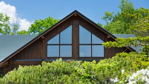 Une cabane en bois avec un toit triangulaire et de grandes fenêtres.