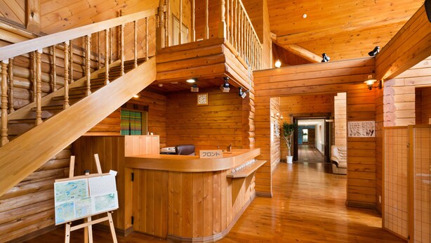 L’intérieur d’un chalet en bois, avec un comptoir d’accueil, un escalier et des tableaux exposés sur des chevalets.