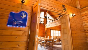 Un intérieur en bois comprenant un espace repas, une enseigne indiquant « Restaurant Yuzuki » et un plafond en bois.