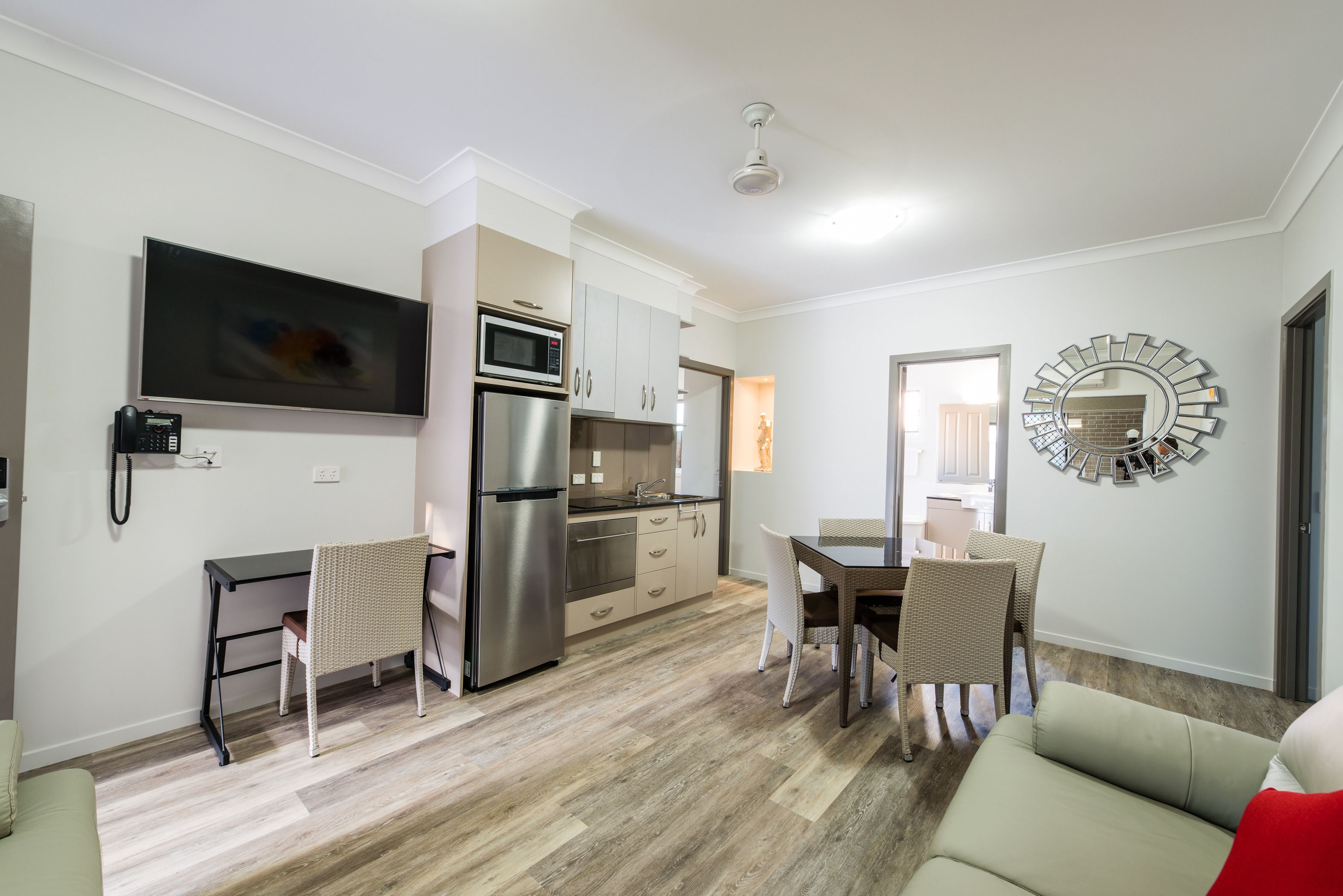 Eine moderne Küche mit Einbau-Mikrowelle, Kühlschrank und Essbereich mit Korbstühlen.