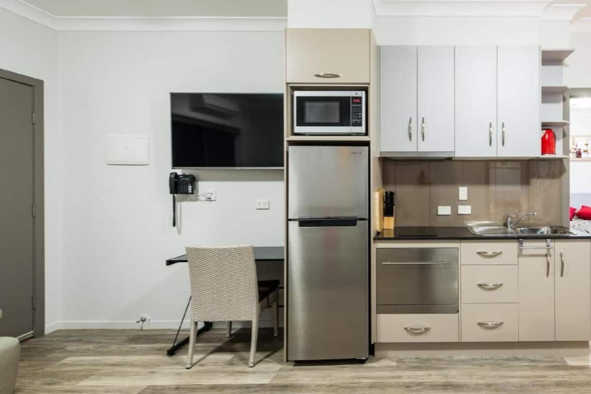 A modern kitchen with a built-in microwave, refrigerator, and a dining area with a chair.