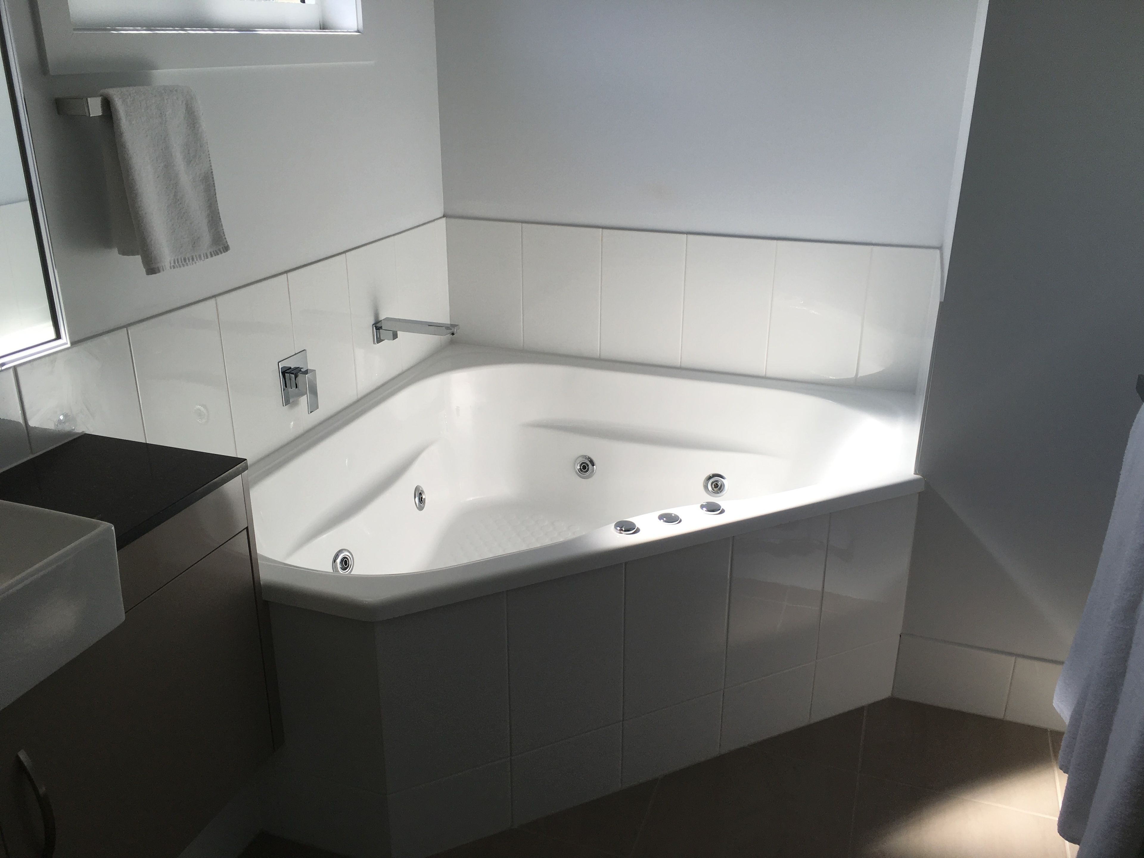 Un baño moderno con una bañera independiente, un tocador con espejo y un perchero para toallas.