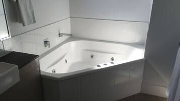 A modern bathroom with a freestanding bathtub, a vanity with a mirror, and a towel rack.