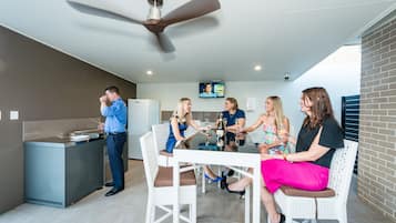 A modern indoor setting with a dining area, a kitchen counter, and a television screen.