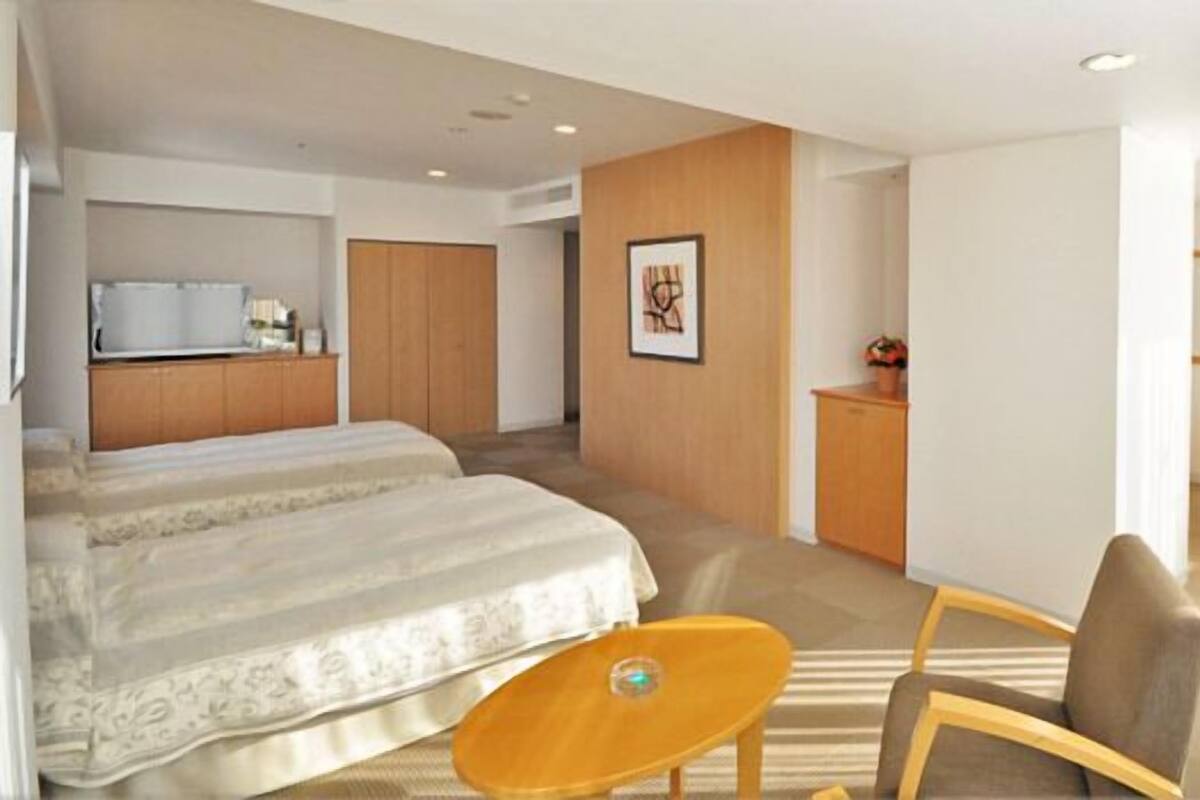 A hotel room with a bed, a desk, a chair, and a small table.