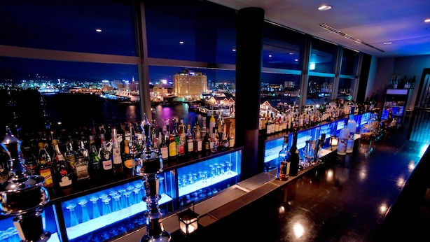 A bar with a city view, bottles, and glasses. - Winning Hotel (Hakodate)