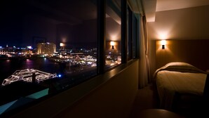 A hotel room with a large window offering a nighttime city view, a bed, and a bedside lamp. - Winning Hotel (Hakodate)