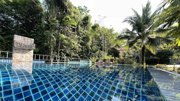 A swimming pool with a grid pattern, surrounded by lush greenery and palm trees. - Chomphu Resort Khaolak (Takua Pa)