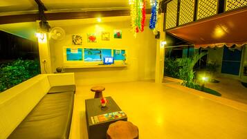 A well-lit indoor area with a sofa, a small table, and a TV screen displaying a contact page.