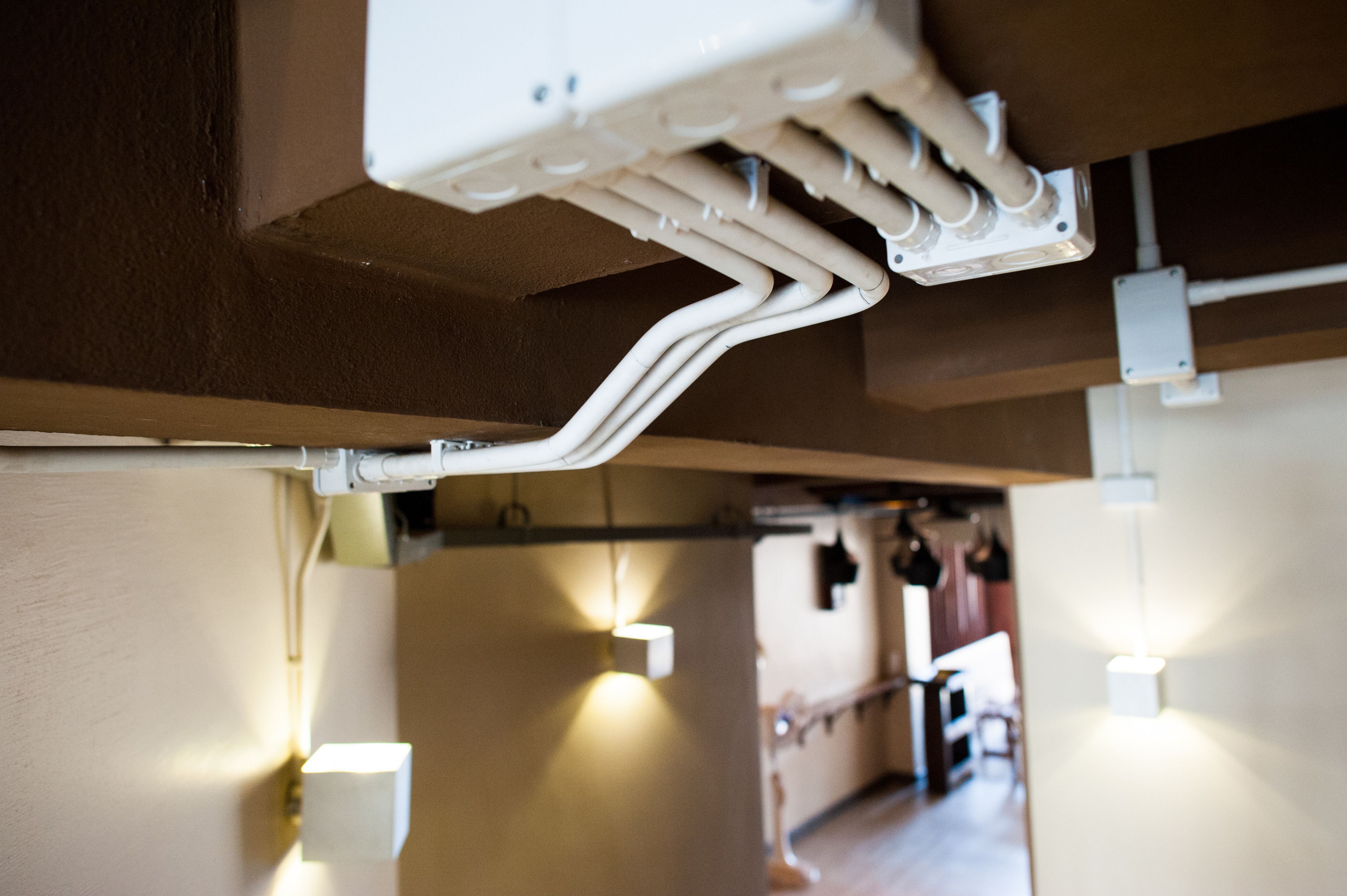 A ceiling with exposed pipes and electrical boxes, suggesting an industrial or unfinished interior.