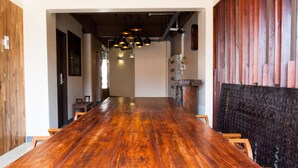 A long wooden dining table with chairs, a wooden wall with circular cutouts, and pendant lighting. - KENCOZY accommodation (Bangkok)