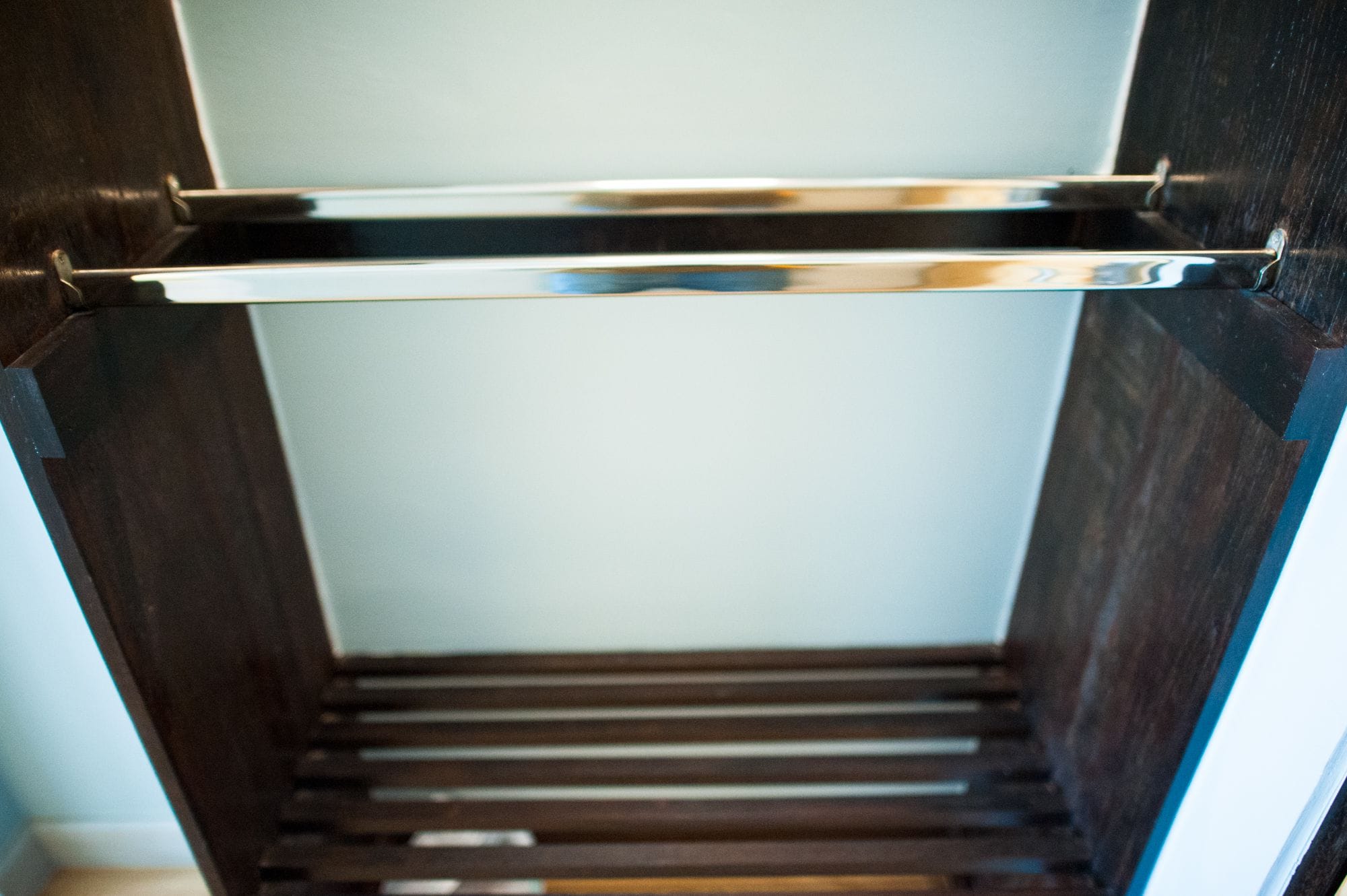 A narrow, wooden stairway leading to a room with a metal shelf.