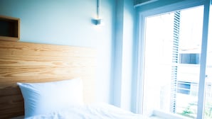 A bedroom with a wooden headboard, a white pillow, and a large window with blinds. - KENCOZY accommodation (Bangkok)