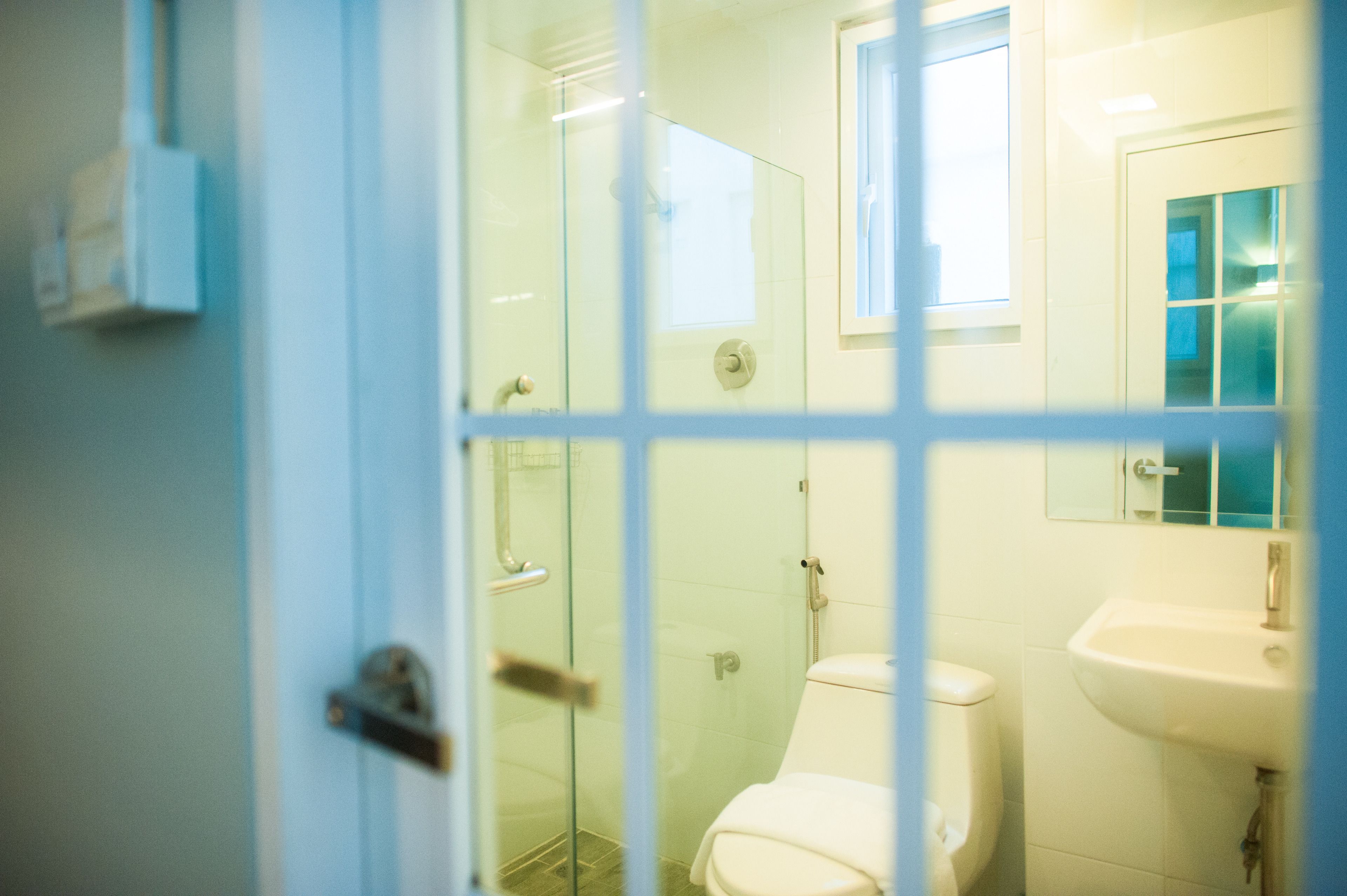 A bathroom with a glass shower enclosure, a white toilet, and a sink with a mirror above it.
