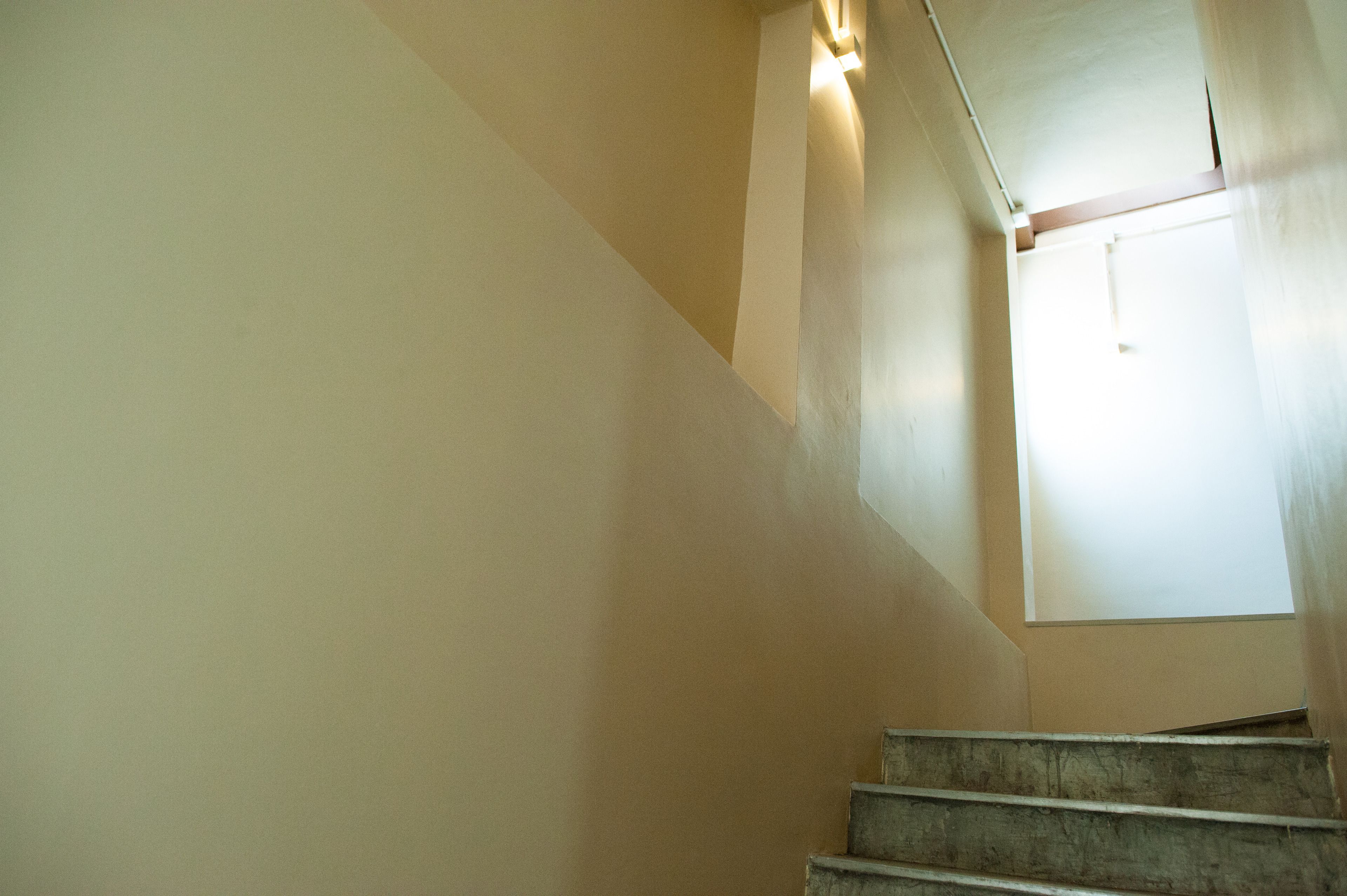 Una escalera con una pared de color claro y una ventana en la parte superior.