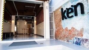 A modern building entrance with a large 'kein' sign on the wall, a glass door, and a metal staircase. - KENCOZY accommodation (Bangkok)