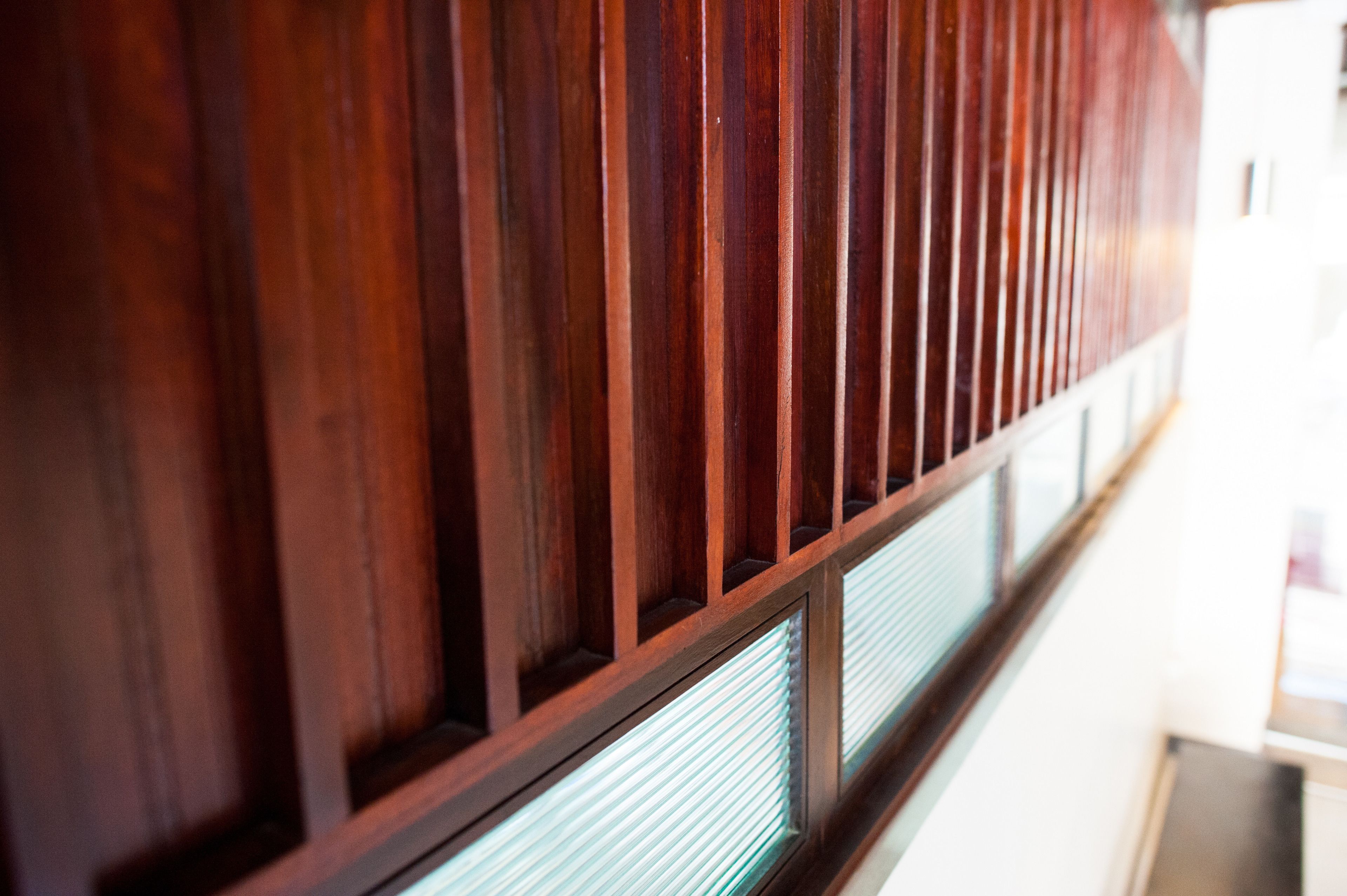 A wooden panel wall with vertical slats and a window with a striped pattern.