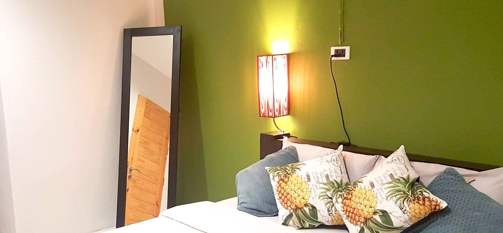 A bed with a wooden headboard, a nightstand with a lamp, and a mirror on the wall.
