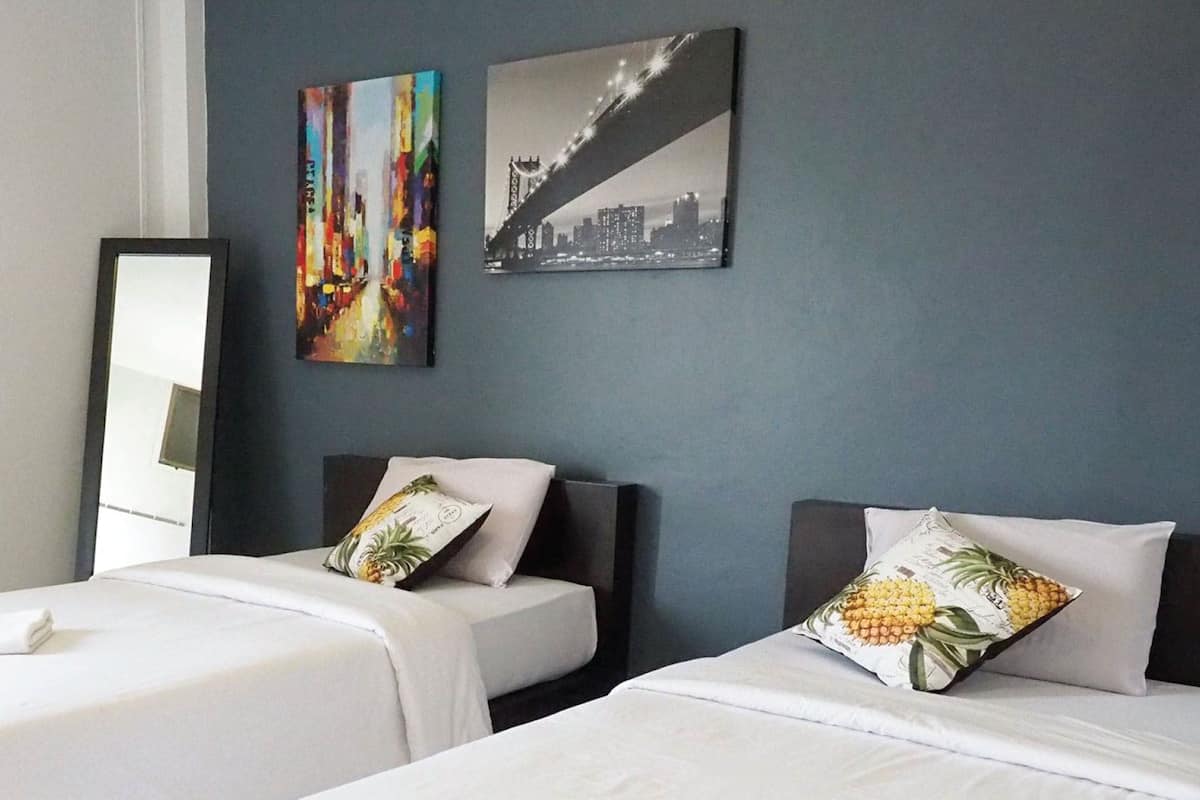 A hotel room with two beds, a large mirror, and two wall-mounted artworks.