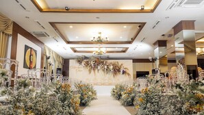Un lieu de réception pour mariage doté d’une allée centrale, de décorations florales et de chaises blanches.