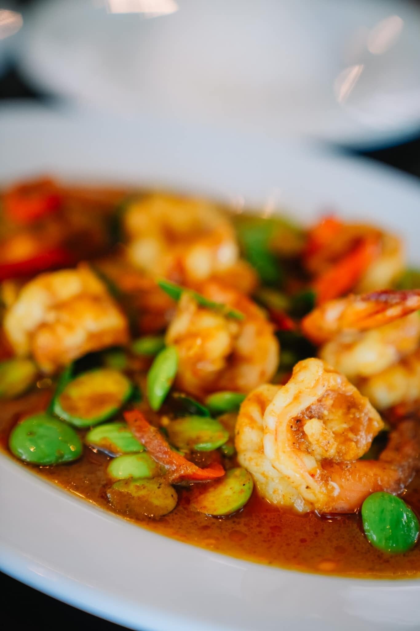 Un plato de camarones con verduras en salsa.