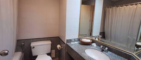 Un baño moderno con inodoro, lavamanos y espejo.