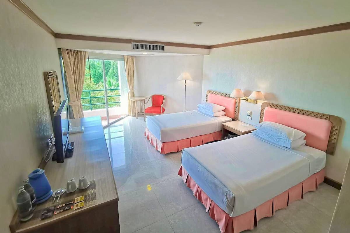 Une chambre d’hôtel avec deux lits, un bureau, une chaise, une télévision et une fenêtre avec des rideaux.