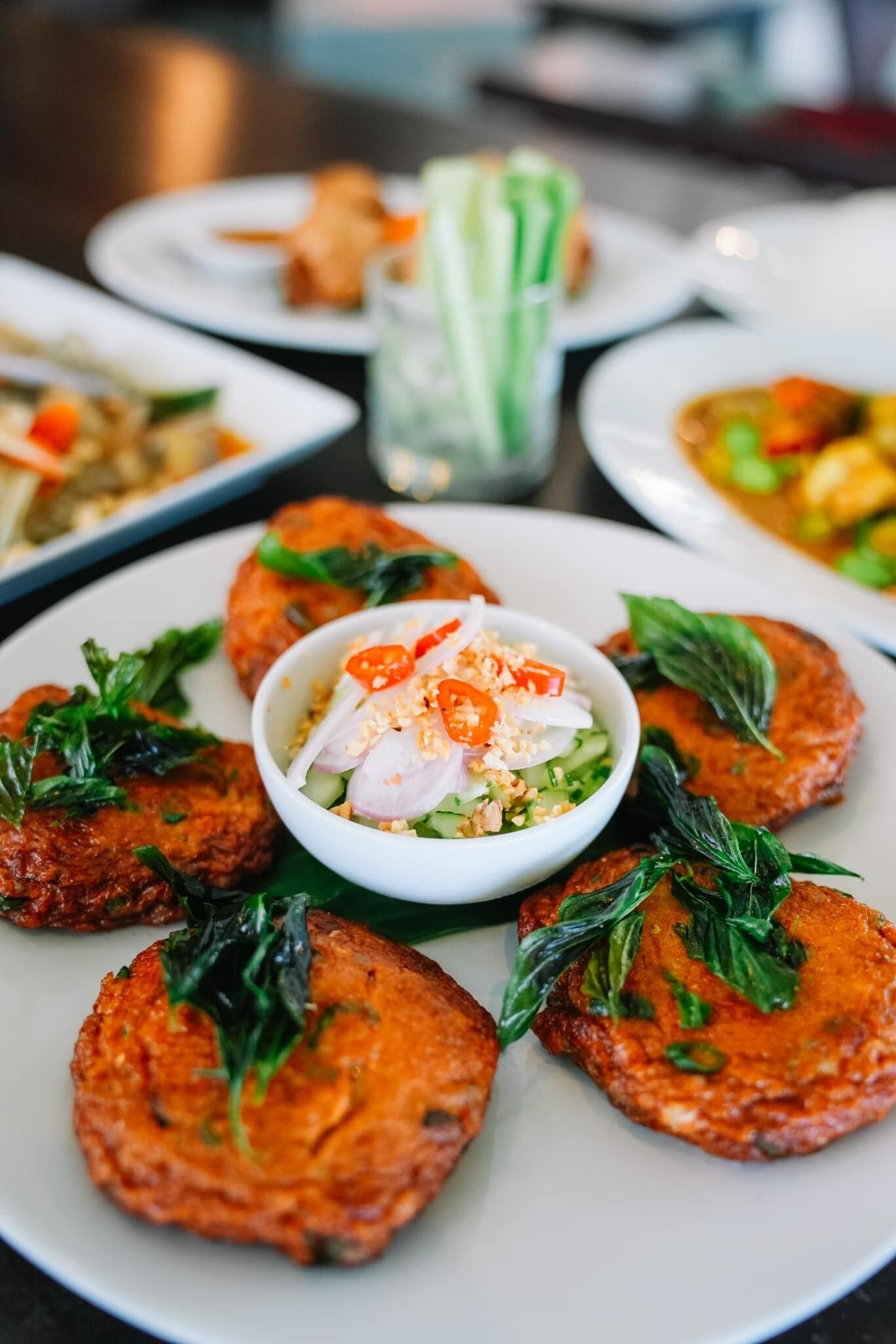 A plate of food with patties and a bowl of salad.