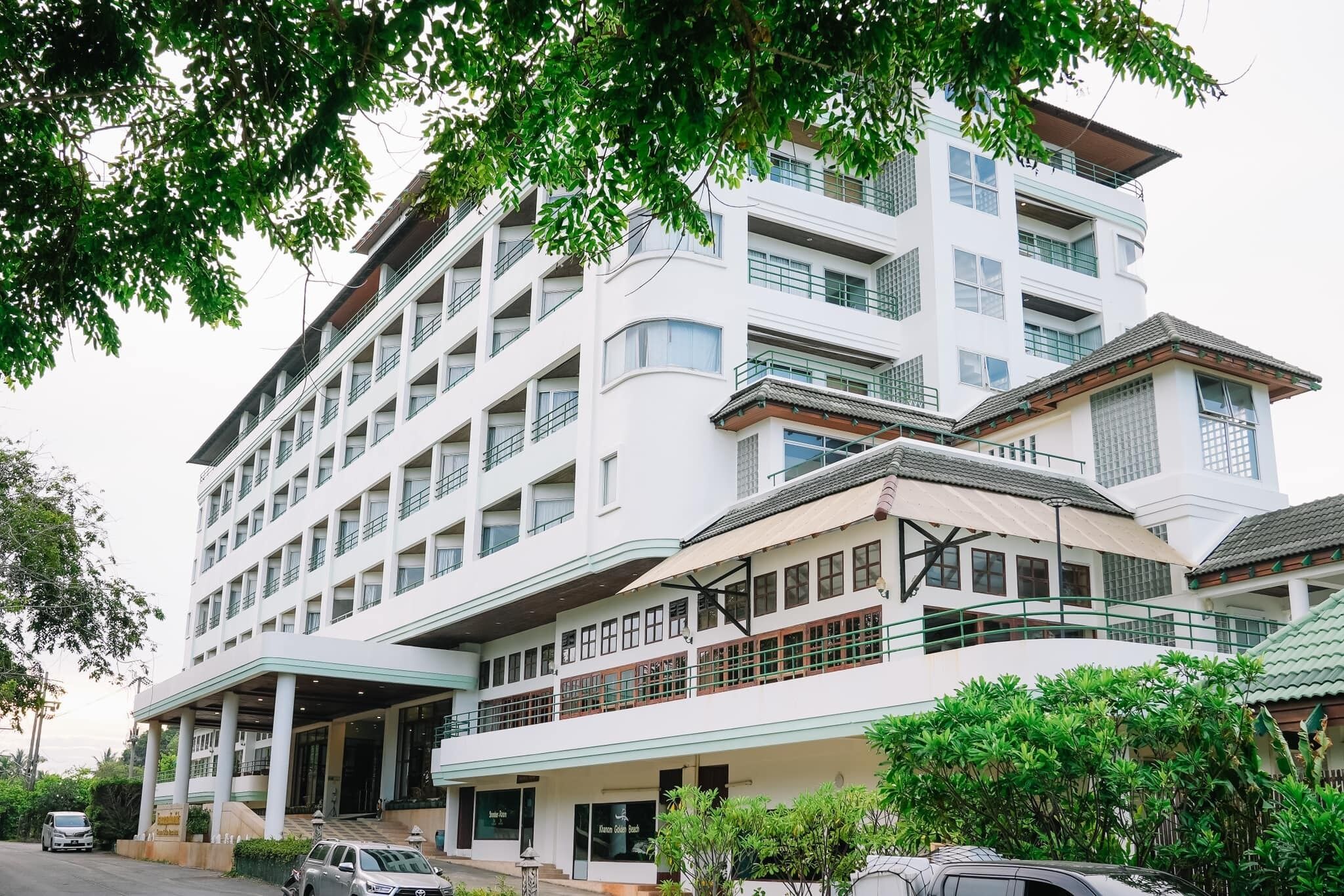 A multi-story hotel with a prominent entrance, balconies, and a covered area.