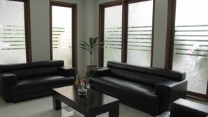 Una sala moderna con dos sofás de cuero negro, una mesa de centro de vidrio y una planta en maceta.