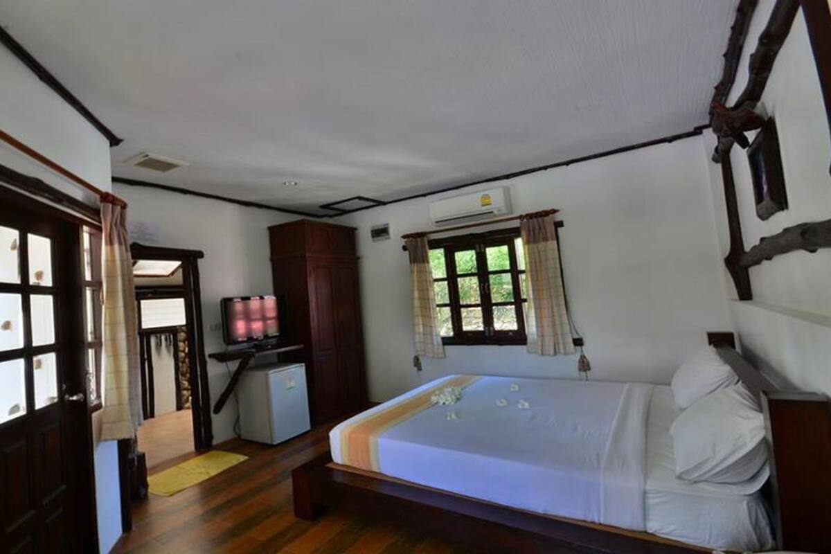 A bedroom with a bed, a desk, a wardrobe, and a window with curtains.