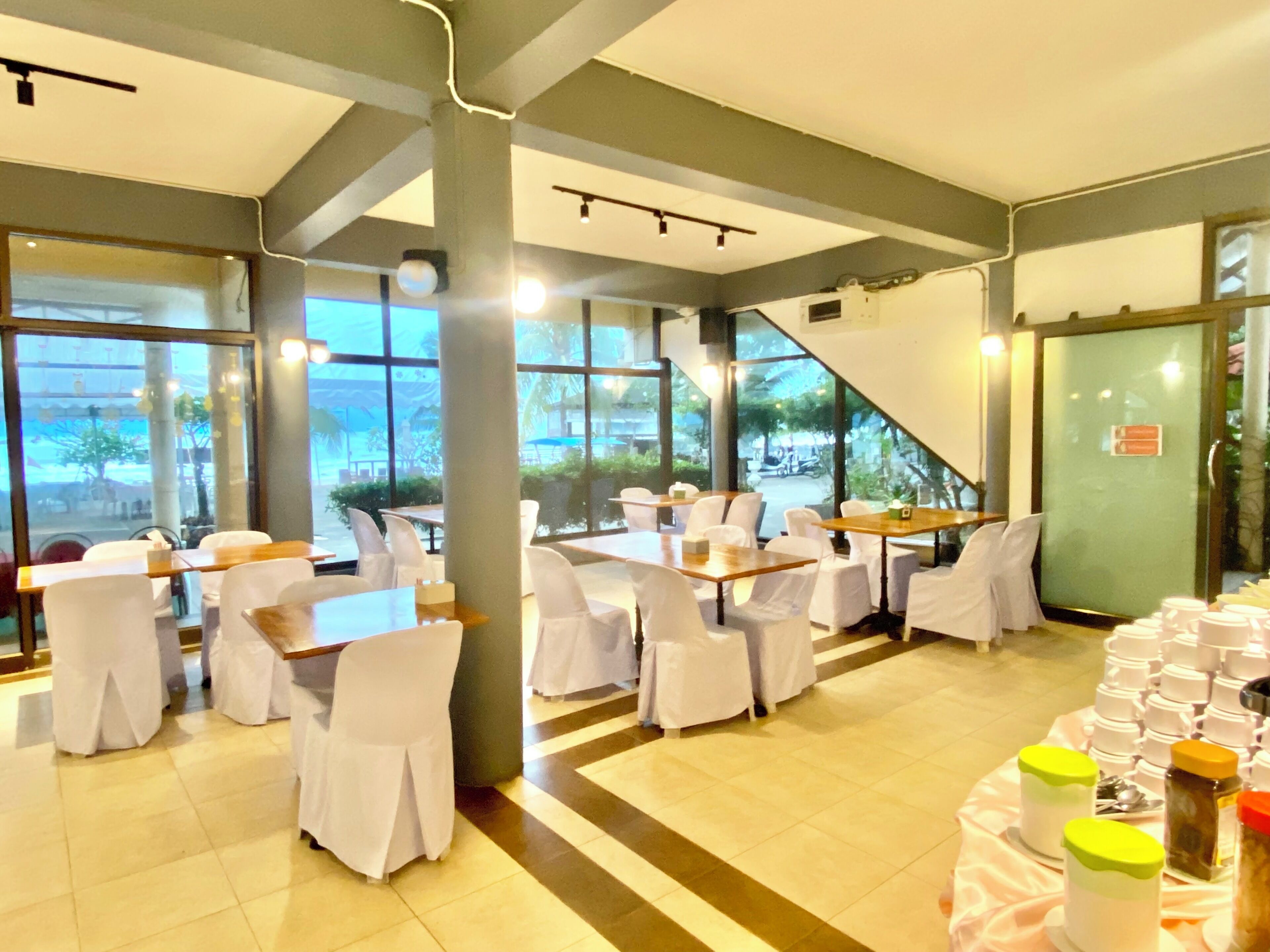 A restaurant with tables and chairs, large windows, and a view of the outside.
