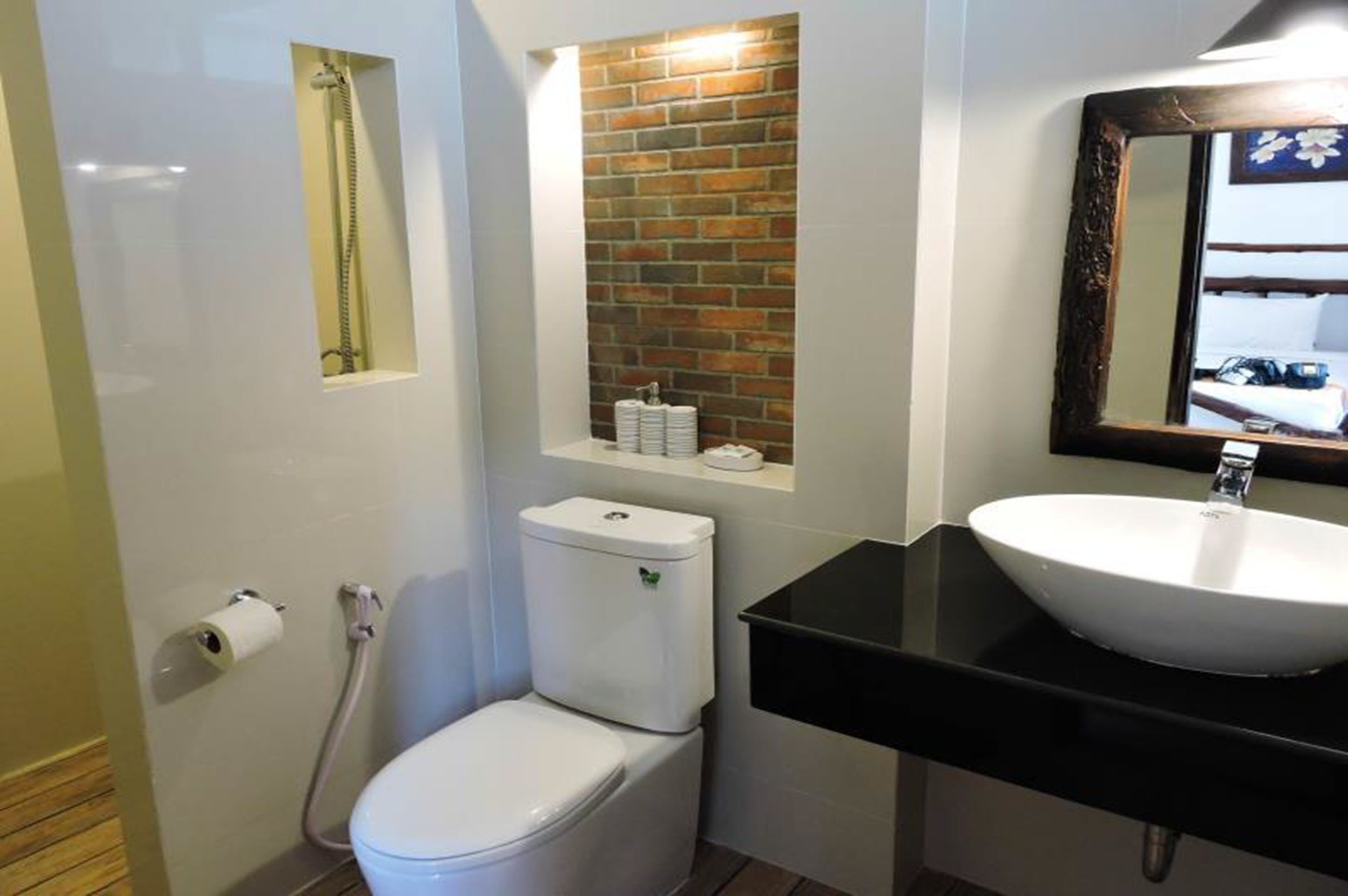 A bathroom with a toilet, a sink, a mirror, and a shower.