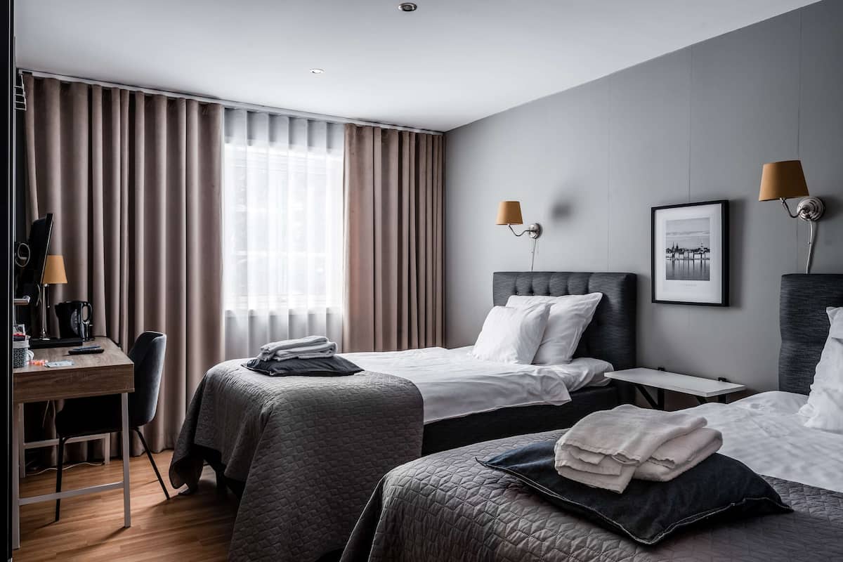 Una habitación de hotel moderna con dos camas, un escritorio y una silla.