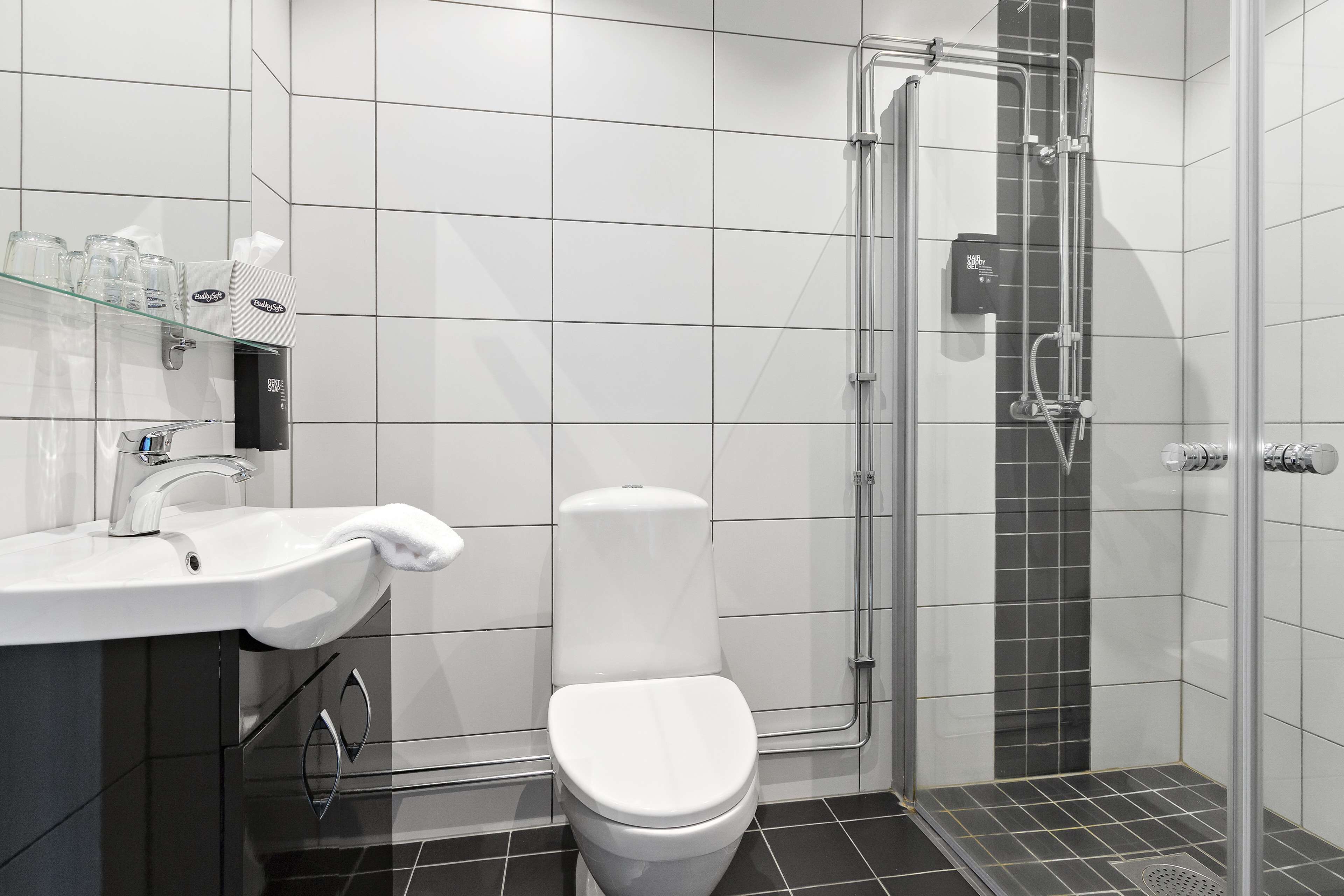 A modern bathroom with a white sink, toilet, and glass shower enclosure.