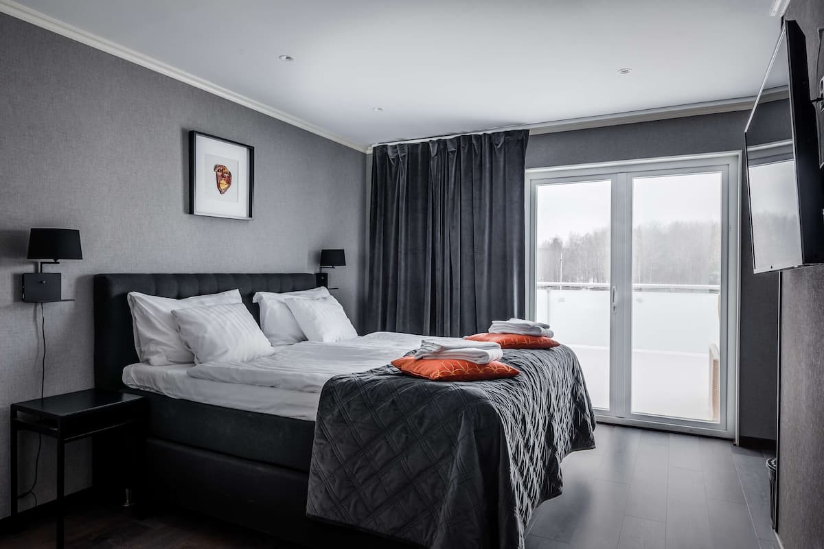 Habitación de hotel moderna con una cama grande, televisor de pantalla plana y vistas al exterior.