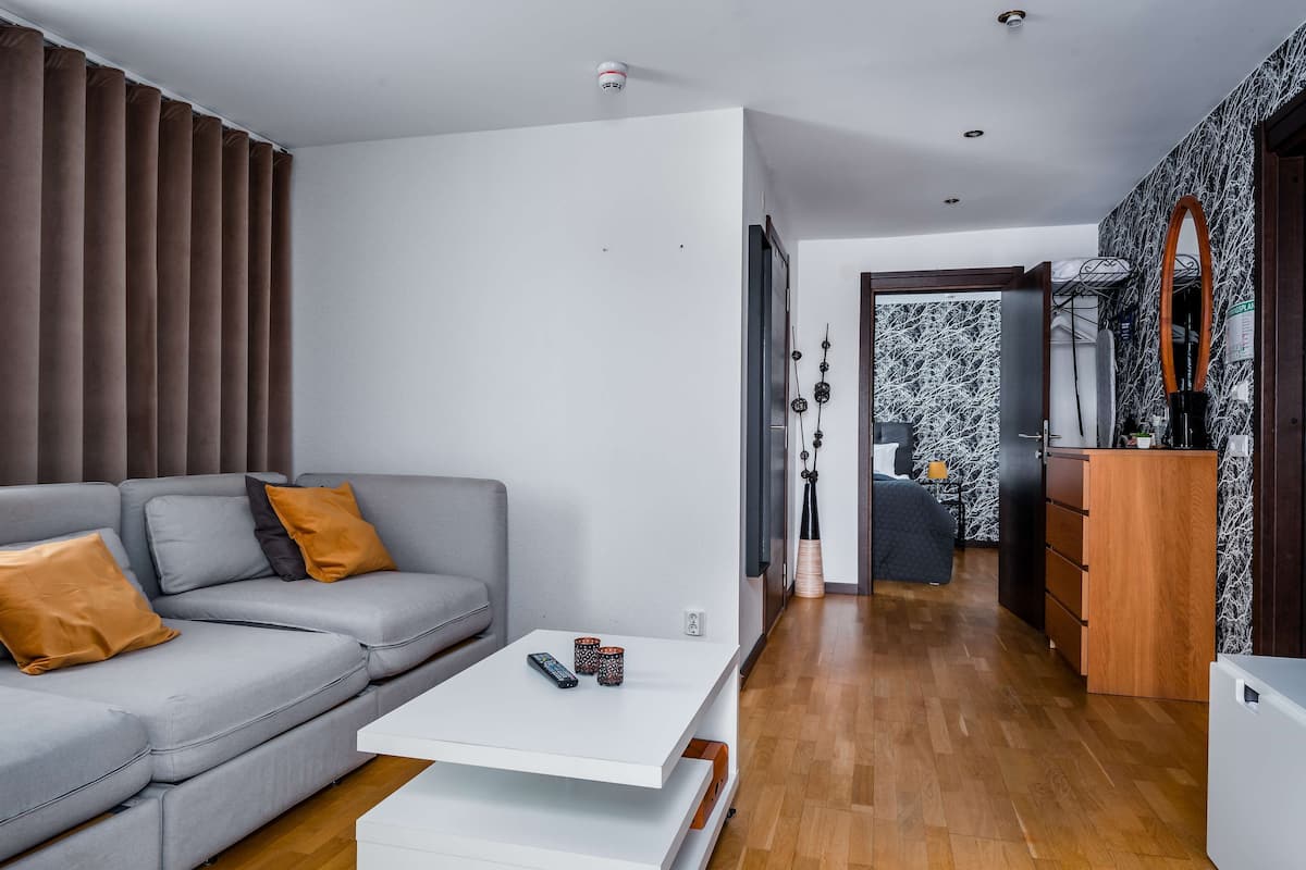 Una sala de estar moderna con un sofá gris, una mesa de centro blanca y piso de madera.