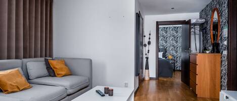 A modern living room with a grey sofa, a white coffee table, and a wooden floor.