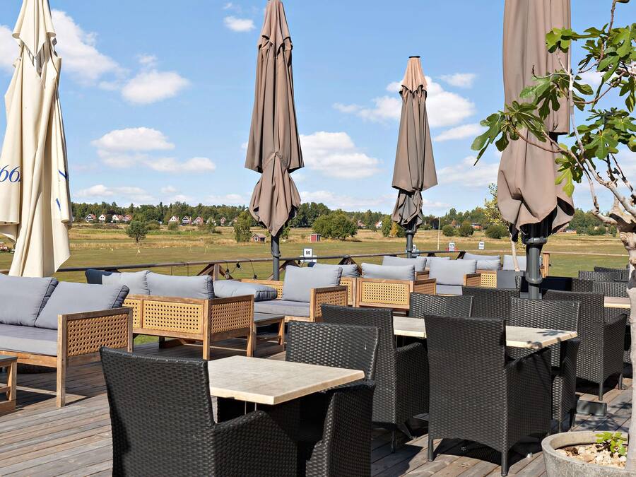 An outdoor seating area with wicker furniture, umbrellas, and a view of the countryside.