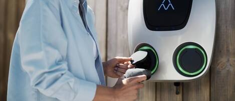 A person interacting with a device mounted on a wooden wall.