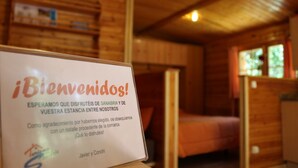A wooden cabin interior with a welcome sign, wooden walls, and a bed.