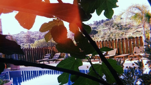 A swimming pool with a wooden deck and lounge chairs, surrounded by a wooden fence and trees. - Il Castello (Piazza Armerina)