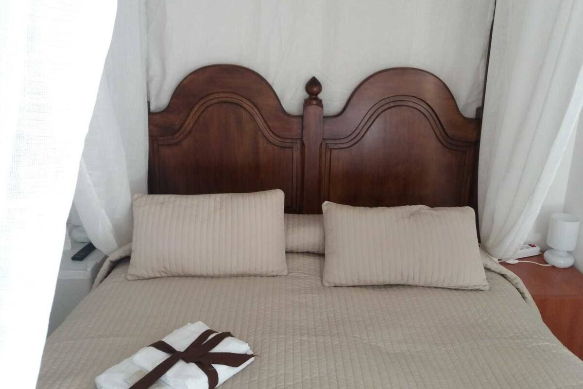 A neatly made bed with a wooden headboard, two pillows, and a folded towel on the bed.