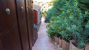 A narrow stone pathway flanked by wooden doors and potted plants. - Il Castello (Piazza Armerina)