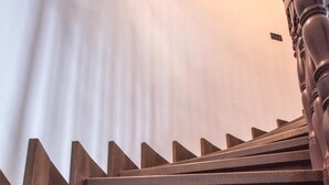 A wooden staircase with a handrail and a light source in the background. - Il Castello (Piazza Armerina)