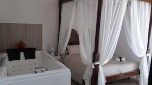 A four-poster canopy bed with a white canopy, a separate bathtub, and a vanity with a mirror and toiletries. - Il Castello (Piazza Armerina)