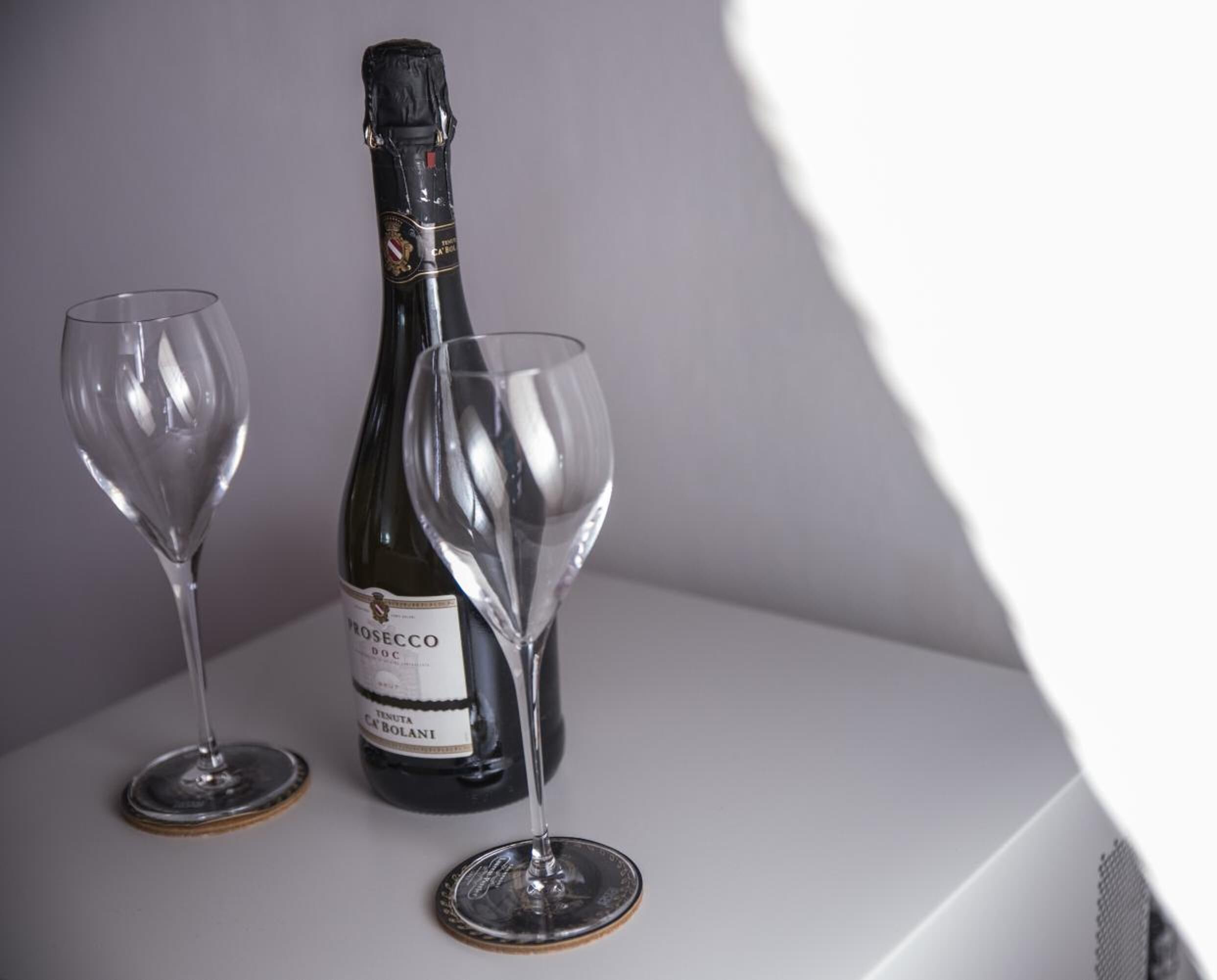 A bottle of wine and two glasses on a white surface.